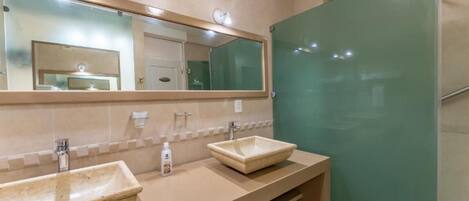 A bathroom with two sinks, a large mirror, and a glass shower enclosure.