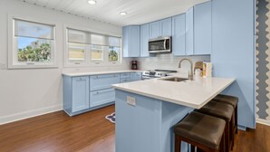 A modern kitchen with blue cabinets, a white countertop, and a built-in microwave.