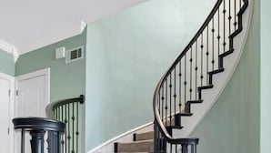 Una escalera con barandilla negra y un rellano cubierto de alfombra beige.
