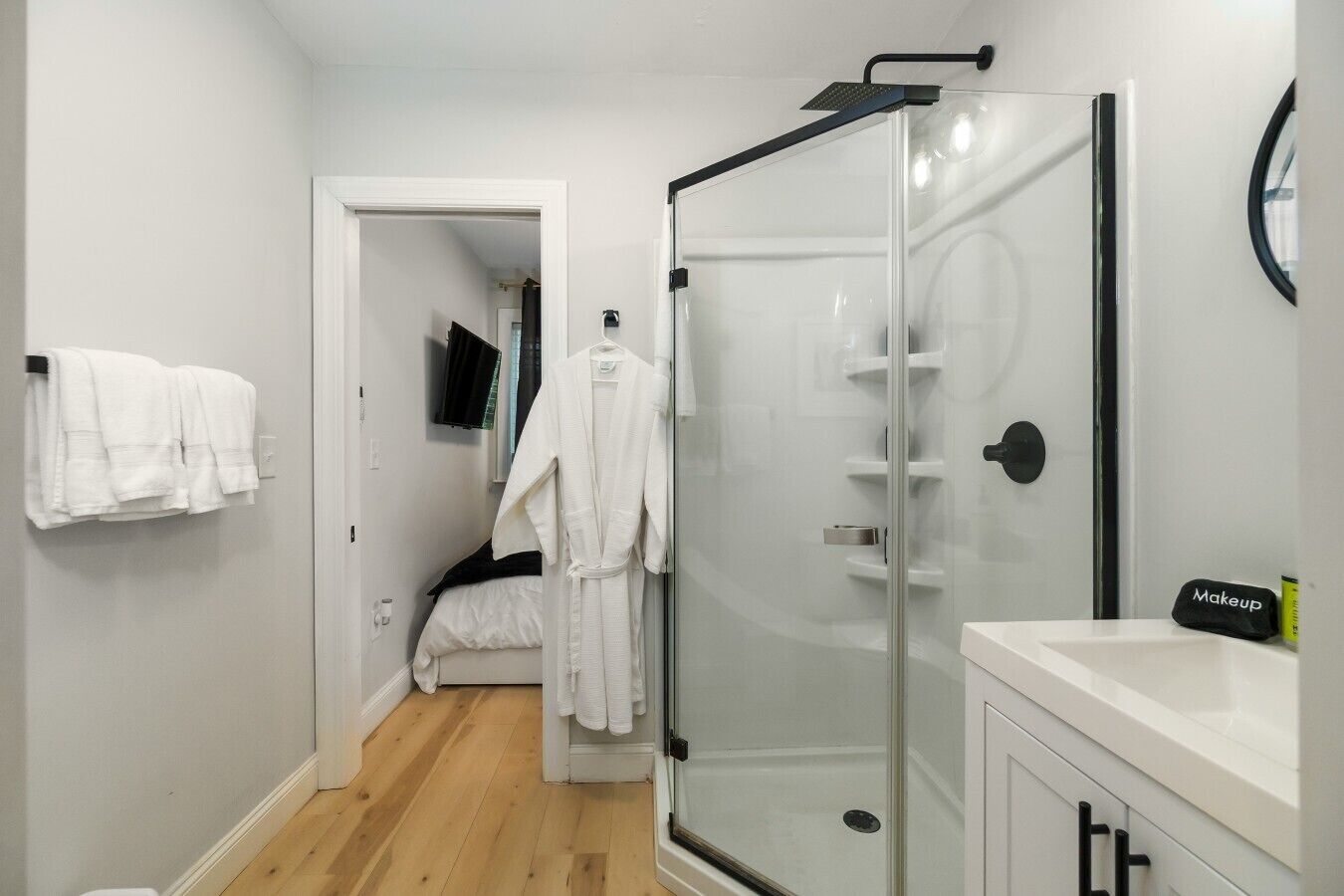 Un bany modern amb plat de dutxa de vidre, un lavabo blanc i un mirall.