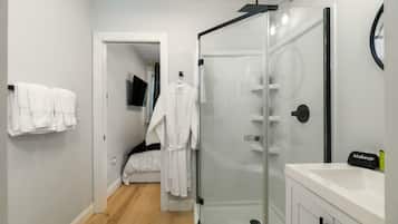Un bany modern amb plat de dutxa de vidre, un lavabo blanc i un mirall.