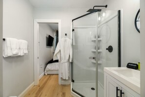 Un baño moderno con cabina de ducha de vidrio, un lavabo blanco y un espejo.