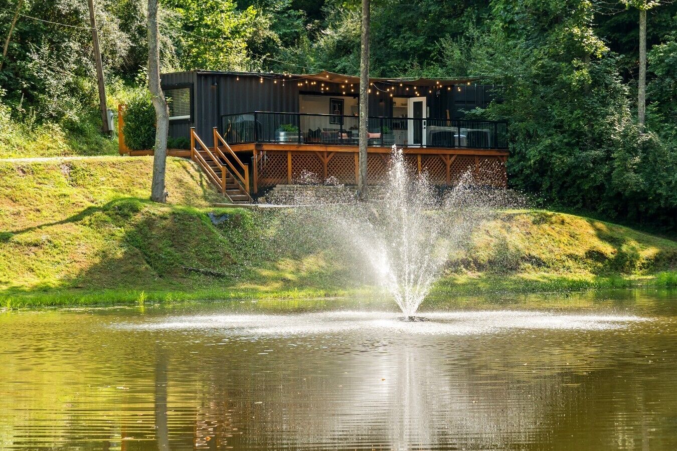 A modern building with a deck, a fountain, and a pond.