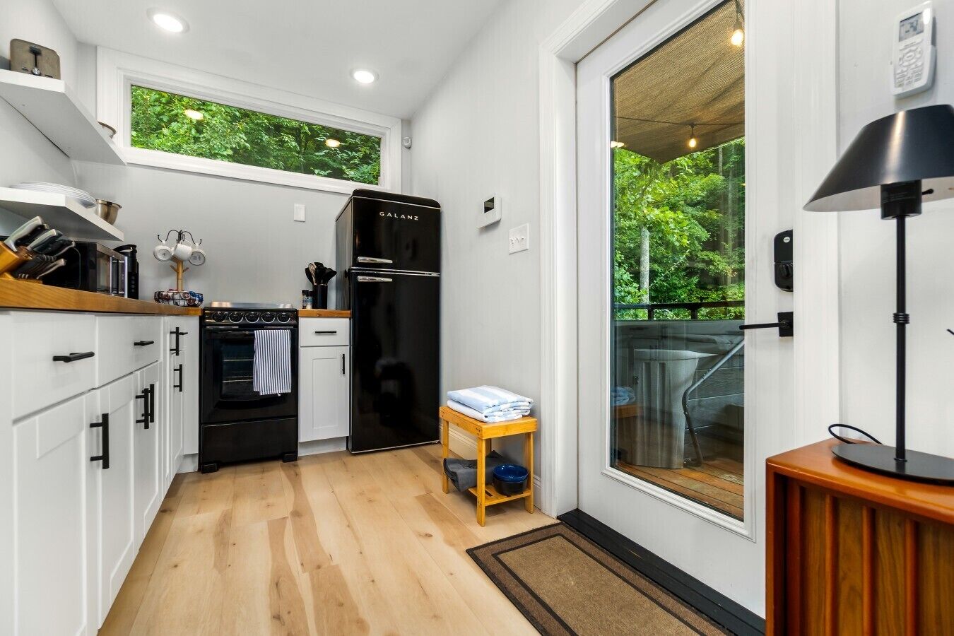 A compact kitchen with white cabinets, a black refrigerator, and a wooden countertop.