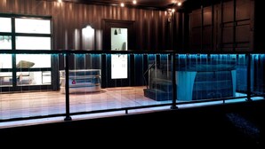 A modern interior with a glass-enclosed balcony, a visible kitchen area, and a large water feature. - The Hideaway on Tacketts Shipping Container (Hurricane)