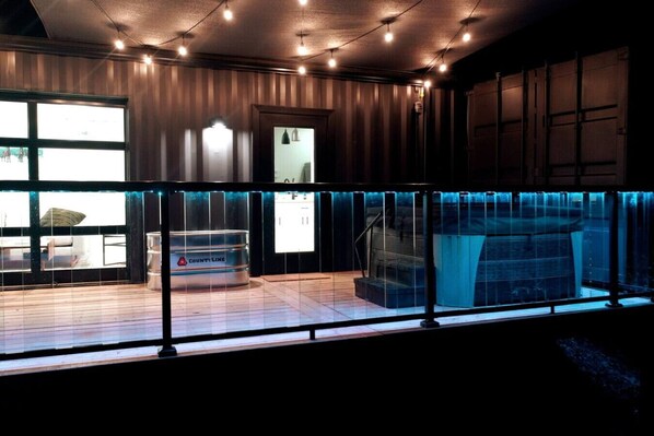 Un interior moderno con balcón de cristal, cocina integrada y una gran fuente de agua.