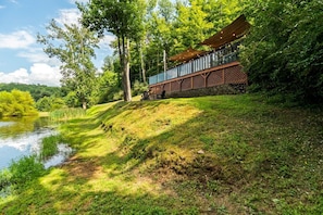 A riverside property with a wooden deck, a covered seating area, and a view of the water. - The Hideaway on Tacketts Shipping Container (Hurricane)