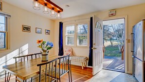 A kitchen with a wooden table and chairs, a vase with flowers, and a view of the outdoors through a door. - Poconos Mountain View Cottage Near Skiing, Hiking   NO CLEANING FEE! (Sciota)