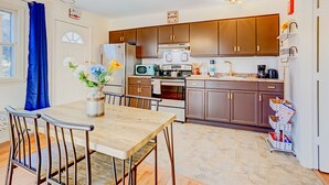 A modern kitchen with wooden cabinets, a dining table with chairs, a refrigerator, an oven, and a microwave. - Poconos Mountain View Cottage Near Skiing, Hiking   NO CLEANING FEE! (Sciota)