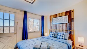A bedroom with a bed, a window, a wooden headboard, and a wall-mounted artwork. - Poconos Mountain View Cottage Near Skiing, Hiking   NO CLEANING FEE! (Sciota)