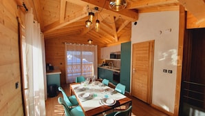 Een houten hut met een eethoek, keuken en een groot raam.