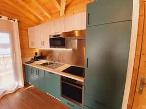 A modern kitchen with wooden ceiling beams, stainless steel appliances, and light blue cabinets.