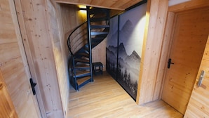 Een houten interieur met een spiltrap, houten wanden en een deur met een bergdecoratie.