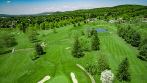 Un campo de golf con varios hoyos, cuerpos de agua y zonas boscosas circundantes.