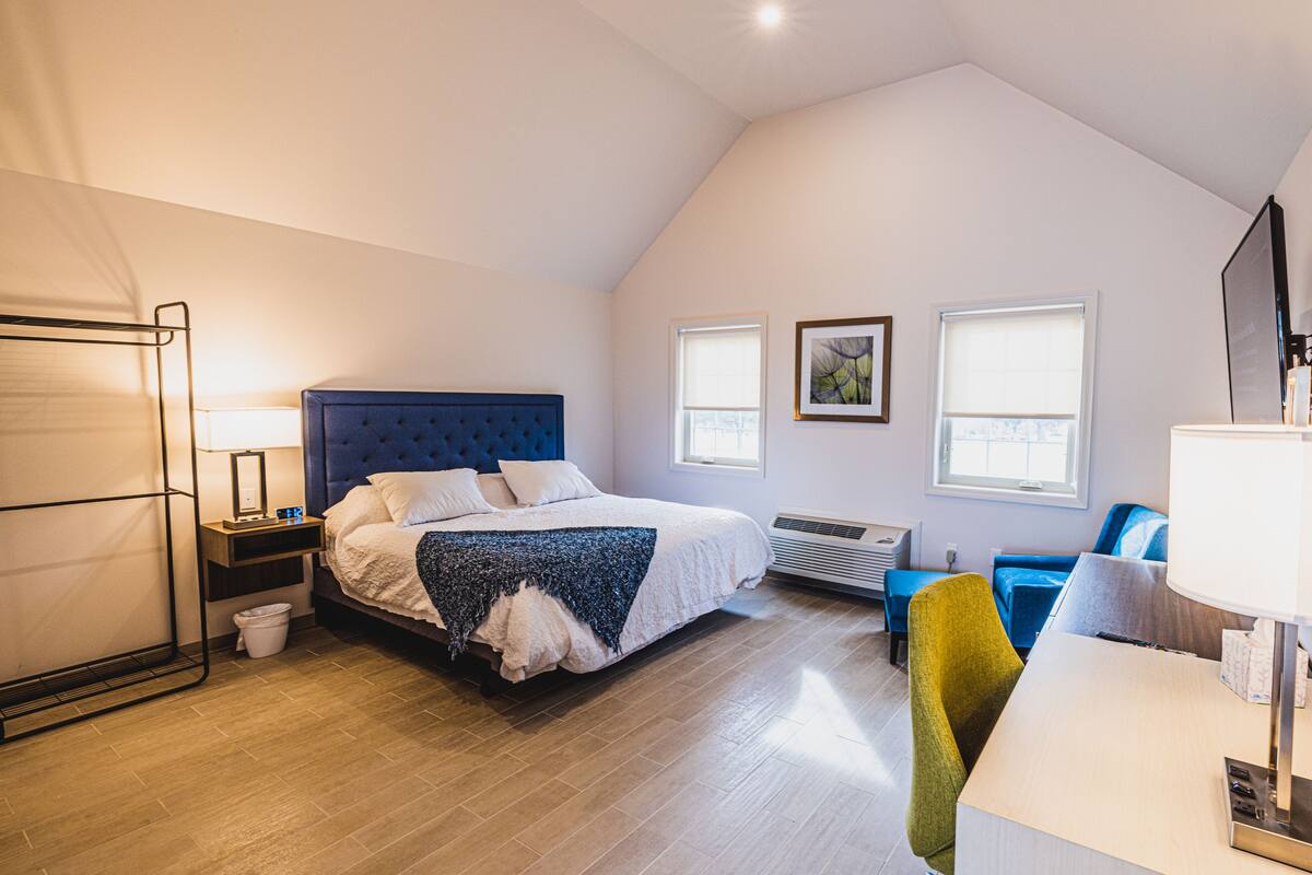 A bedroom with a bed, bedside tables, a desk, a chair, a TV, and a window.