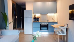 Una cocina moderna con armarios blancos, horno empotrado y un comedor con mesa y sillas.