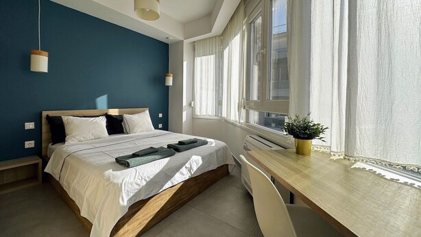 Un dormitorio moderno con cama, mesitas de noche, escritorio y ventana.