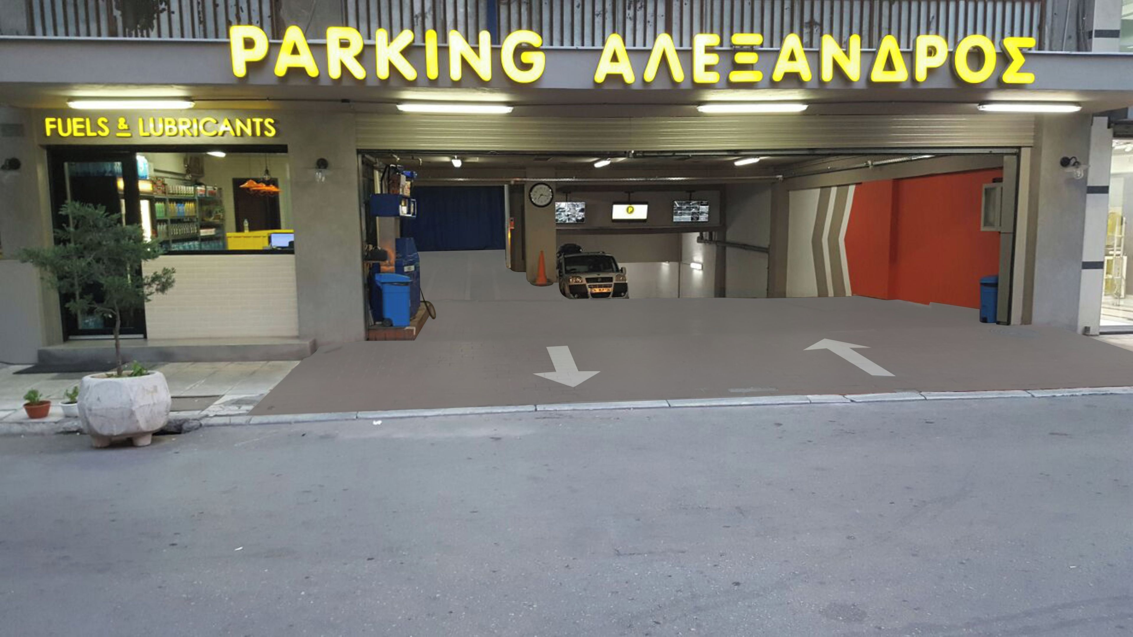 A parking garage entrance with directional arrows on the ground, a fuel station on the left, and a sign for 'PARKING ALEXANAPOΣ'.