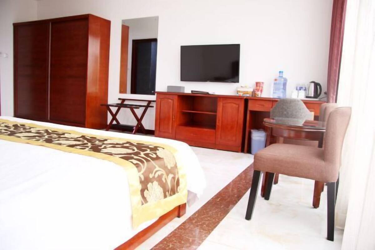 A hotel room with a bed, a desk, a television, and a wardrobe.
