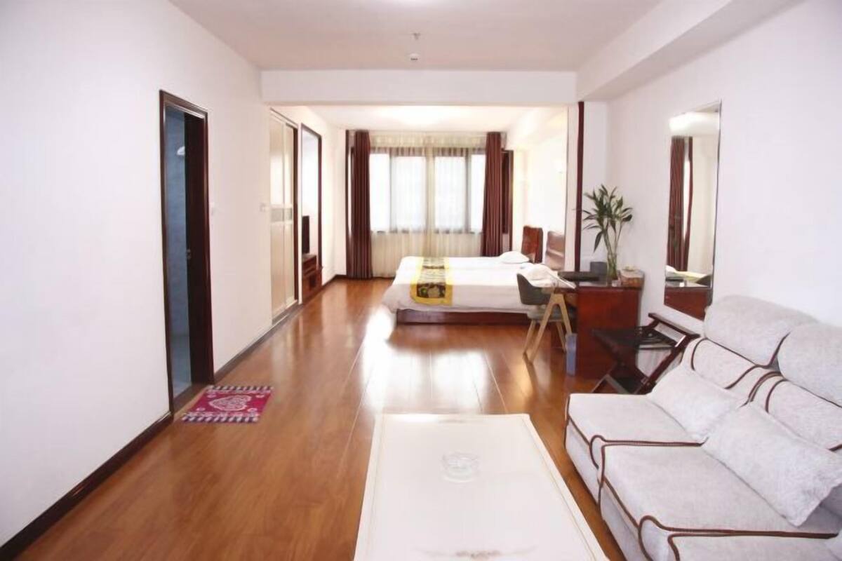 A hotel room with a bed, a sofa, a desk, and a mirror.