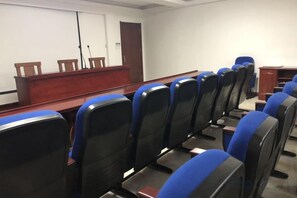 A conference room with rows of chairs, a podium, and a door. - Jinda Business Hotel (Jiaozhou)