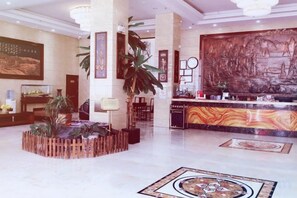 A lobby with a reception desk, a large mural, and a decorative fountain.