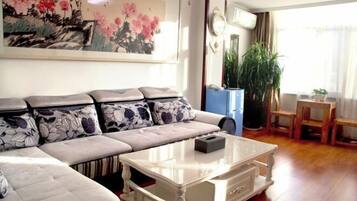 A living room with a sofa, a coffee table, and a painting on the wall.
