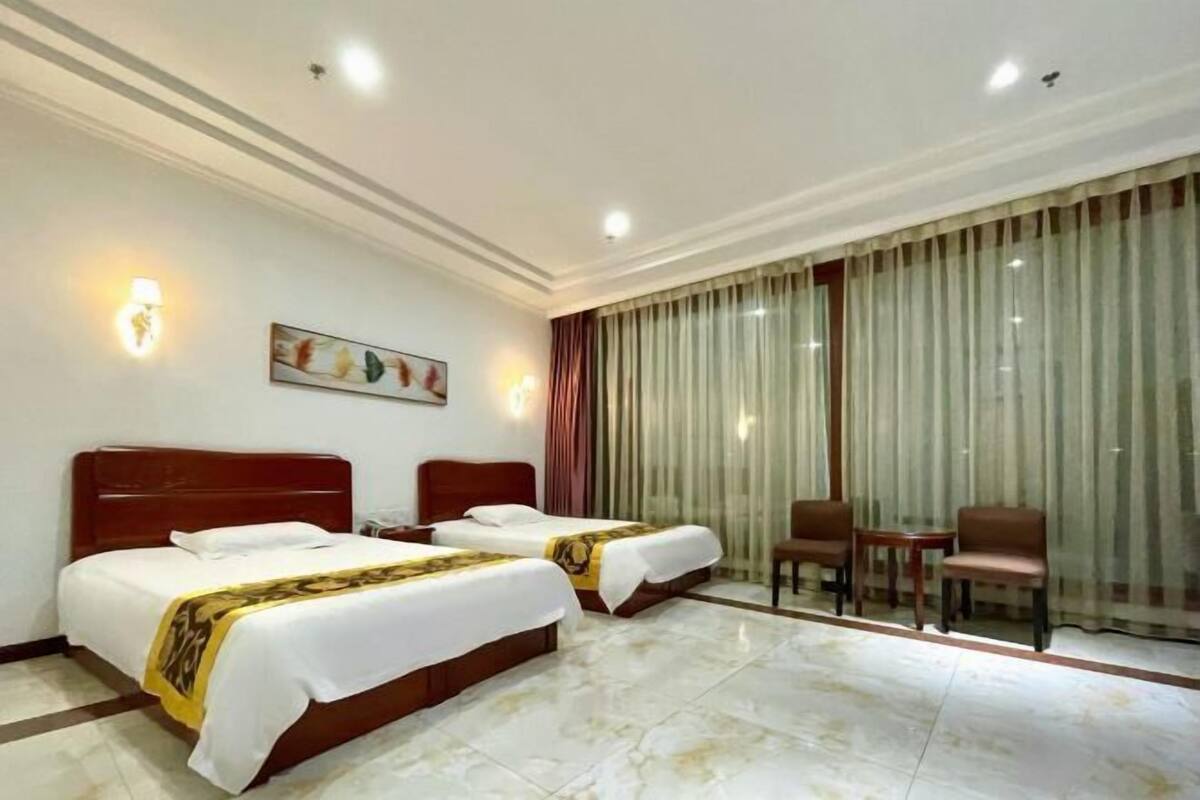 A hotel room with two beds, a small table, and a chair.