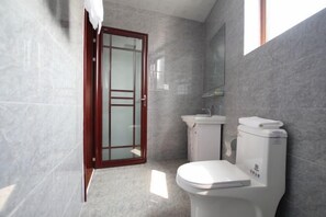 Un bagno con toilette, lavabo e porta in vetro che dà accesso alla zona doccia.