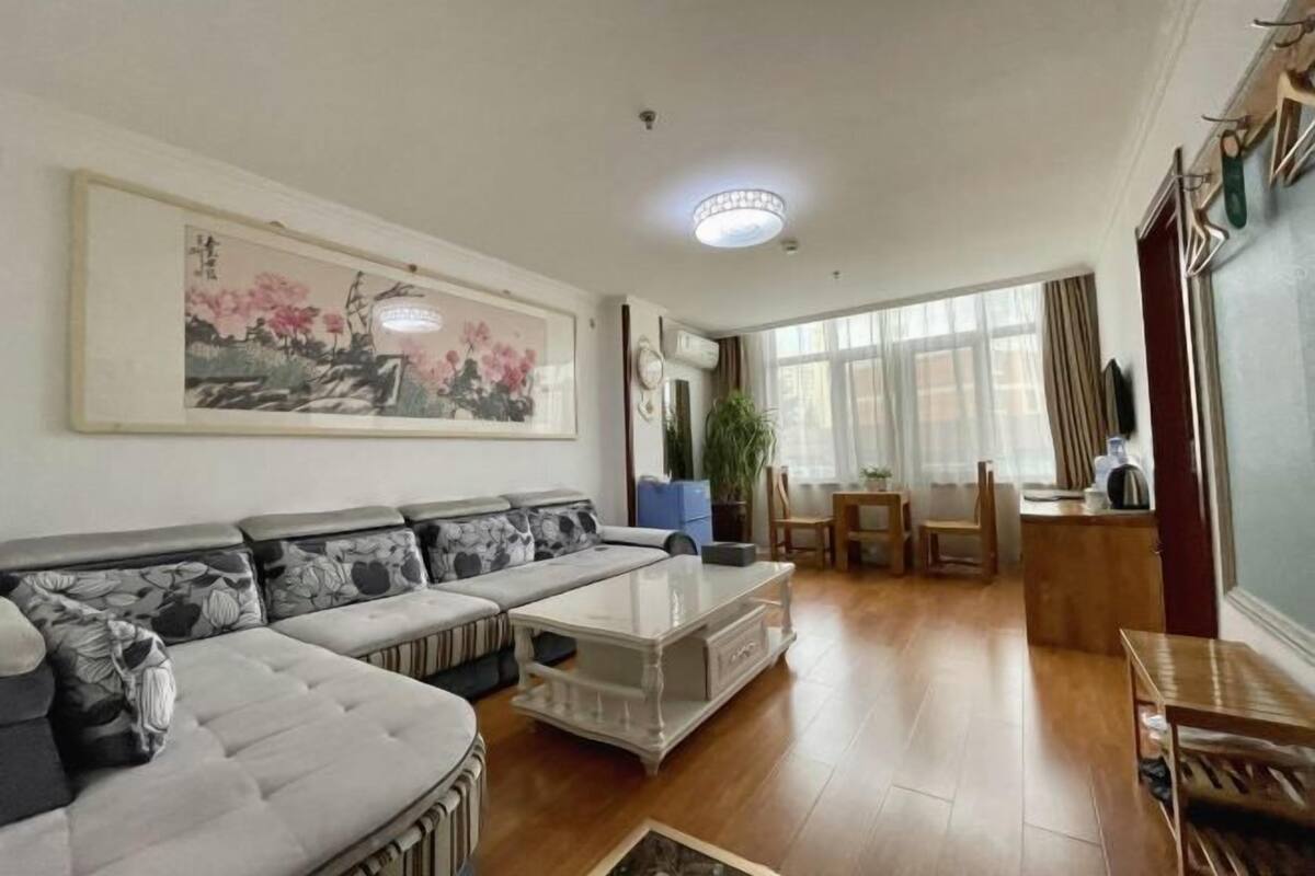 A living room with a sofa, a coffee table, a painting, and a dining area with chairs and a table.