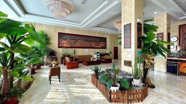 Eine großzügige Lobby mit einem imposanten Chandelier, einer Sitzecke mit Sofas und verschiedenen Kübelpflanzen.