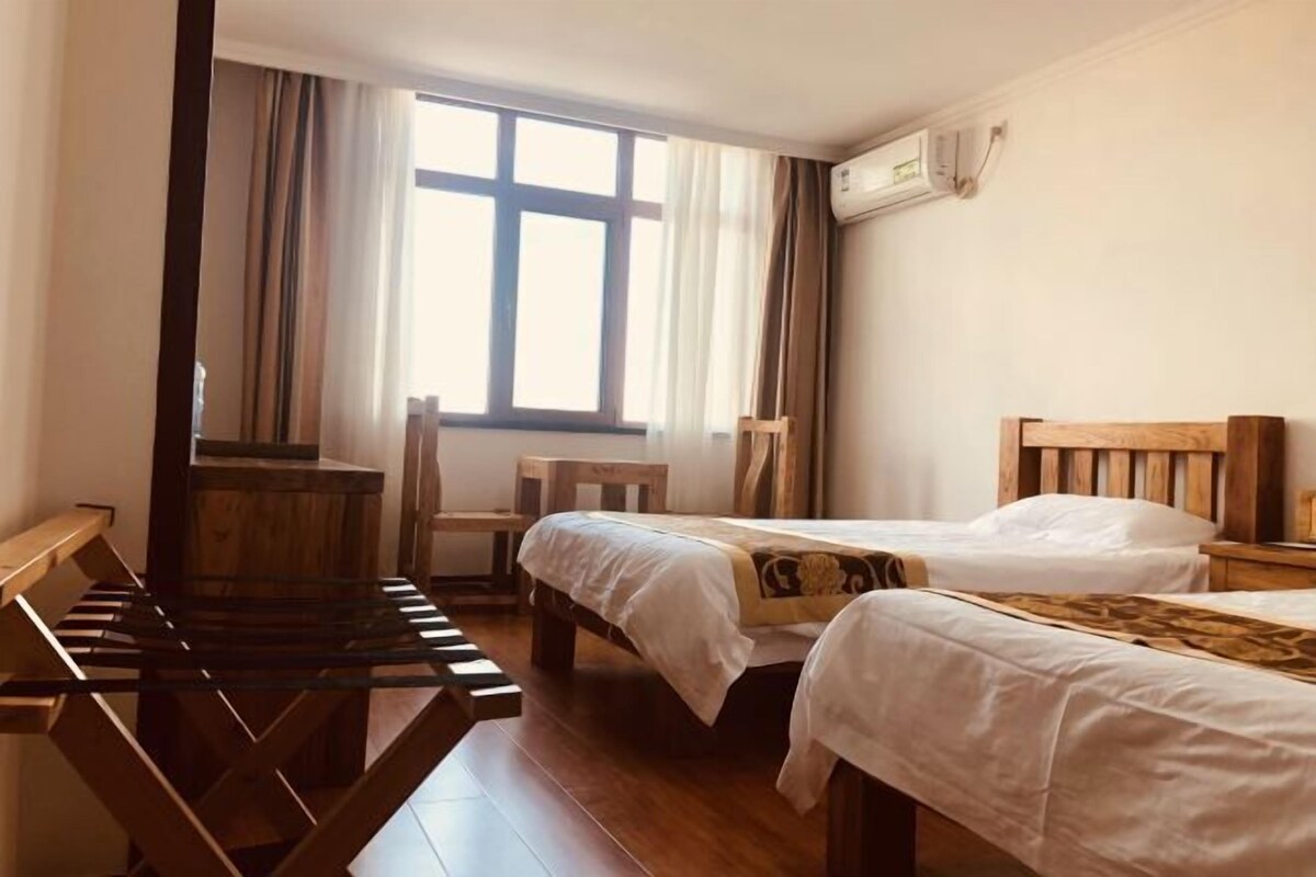 Een hotelkamer met twee bedden, een houten bureau en een stoel.