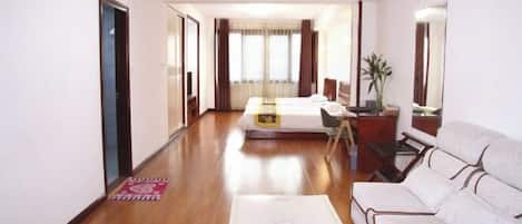A hotel room with a bed, a sofa, a desk, and a mirror.