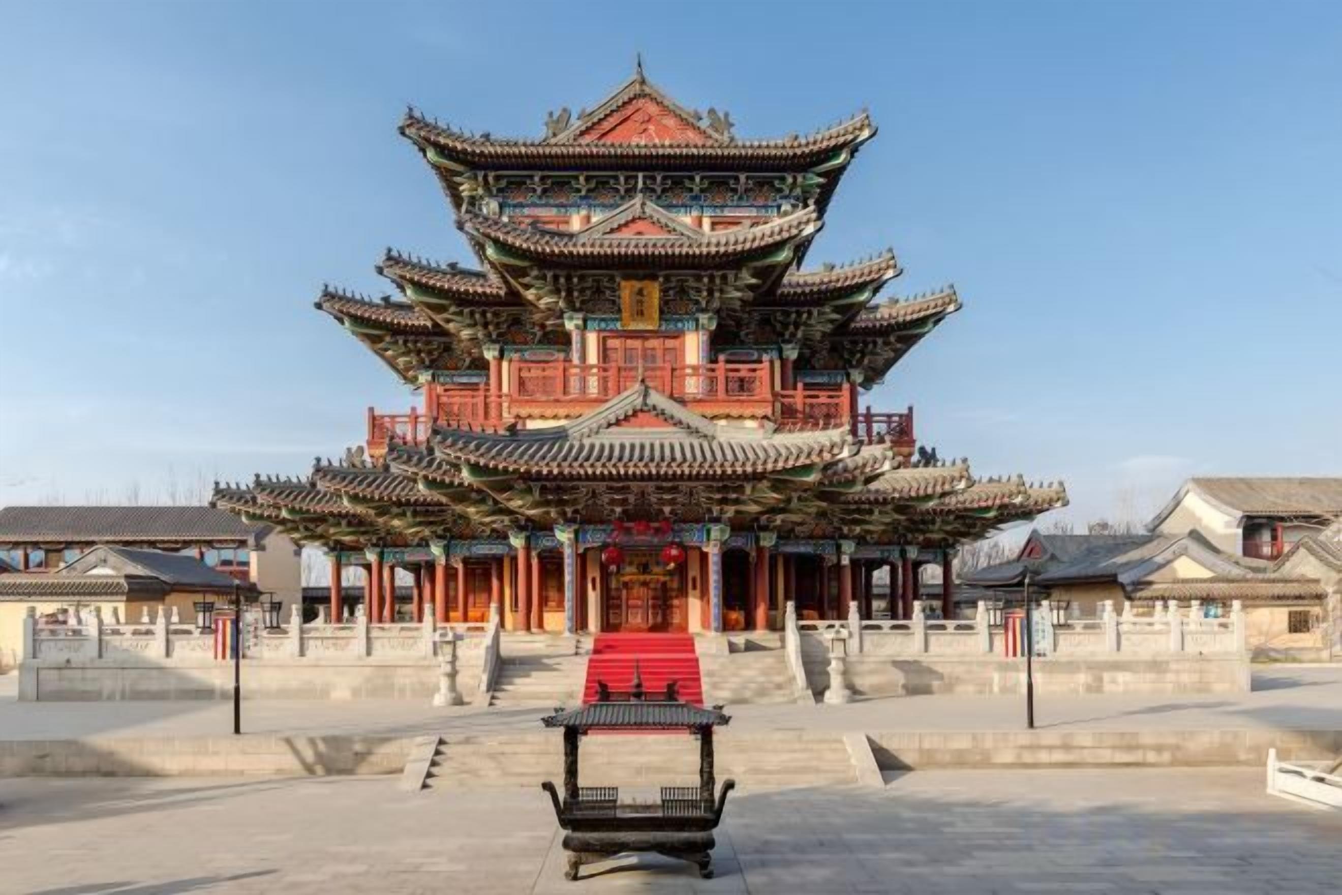 A traditional multi-tiered building with a red carpet leading to the entrance.