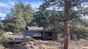 Eine rustikale Holzhütte, umgeben von Kiefern und felsigem Gelände.