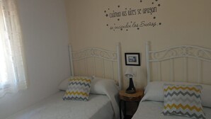 A bedroom with two beds, each with a patterned pillow, a bedside table with a lamp, and a wall decoration with text and stars. - Villa Aurora El Gastor by Ruralidays (Cádiz)