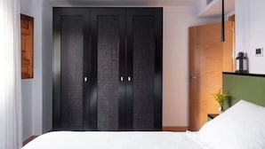 Quarto moderno com uma cama grande, um guarda-roupa escuro e uma parede verde de destaque.