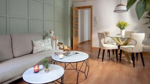 Uma sala de estar moderna com um sofá, duas mesas redondas e um espaço de jantar com cadeiras.