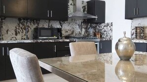 A modern kitchen with dark cabinets, a stainless steel microwave, and a marble countertop. - Endless,upscale four bedroom. (Cabo San Lucas)