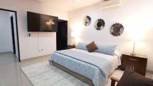 A bedroom with a bed, bedside tables, a TV mounted on the wall, and decorative wall art. - Endless,upscale four bedroom. (Cabo San Lucas)