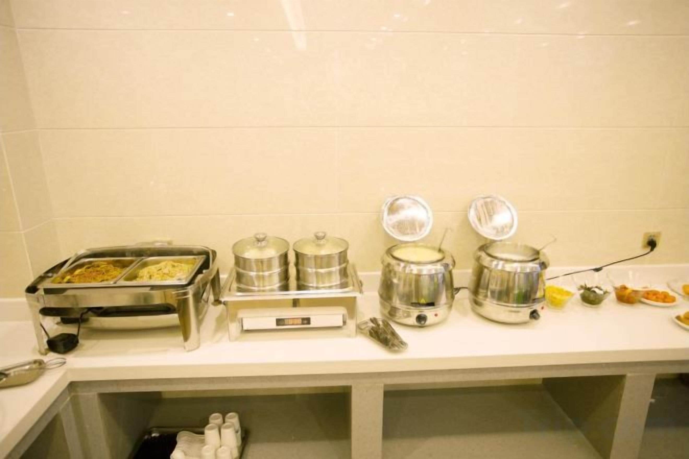 Disposição de buffet com recipientes de comida e máquina de café.