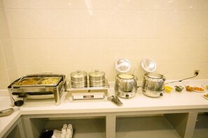 A buffet setup with food containers and a coffee machine.