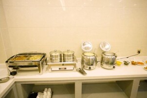 Montaje de bufé con recipientes de comida y una máquina de café.