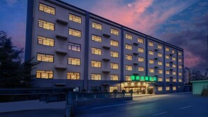 Ett hotell med flera våningar, en modern fasad, stora fönster och en tydligt markerad entré med skyltar.
