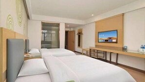 Ett hotellrum med två sängar, en tv, ett skrivbord och ett badrum som syns genom en öppen dörr.
