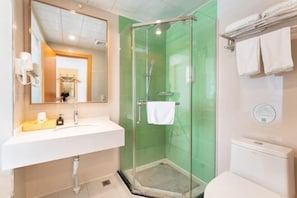 A bathroom with a glass-enclosed shower, a white sink, and a toilet.