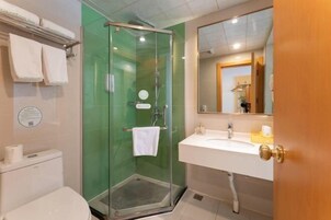 Un baño con ducha de vidrio, un lavamanos blanco y un espejo sobre él.