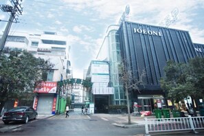 A building with a prominent 'JOONE' sign, a pedestrian crossing, and a street with parked cars. - GreenTree Inn (Suzhou Si County Luanhe Avenue) (Si County)