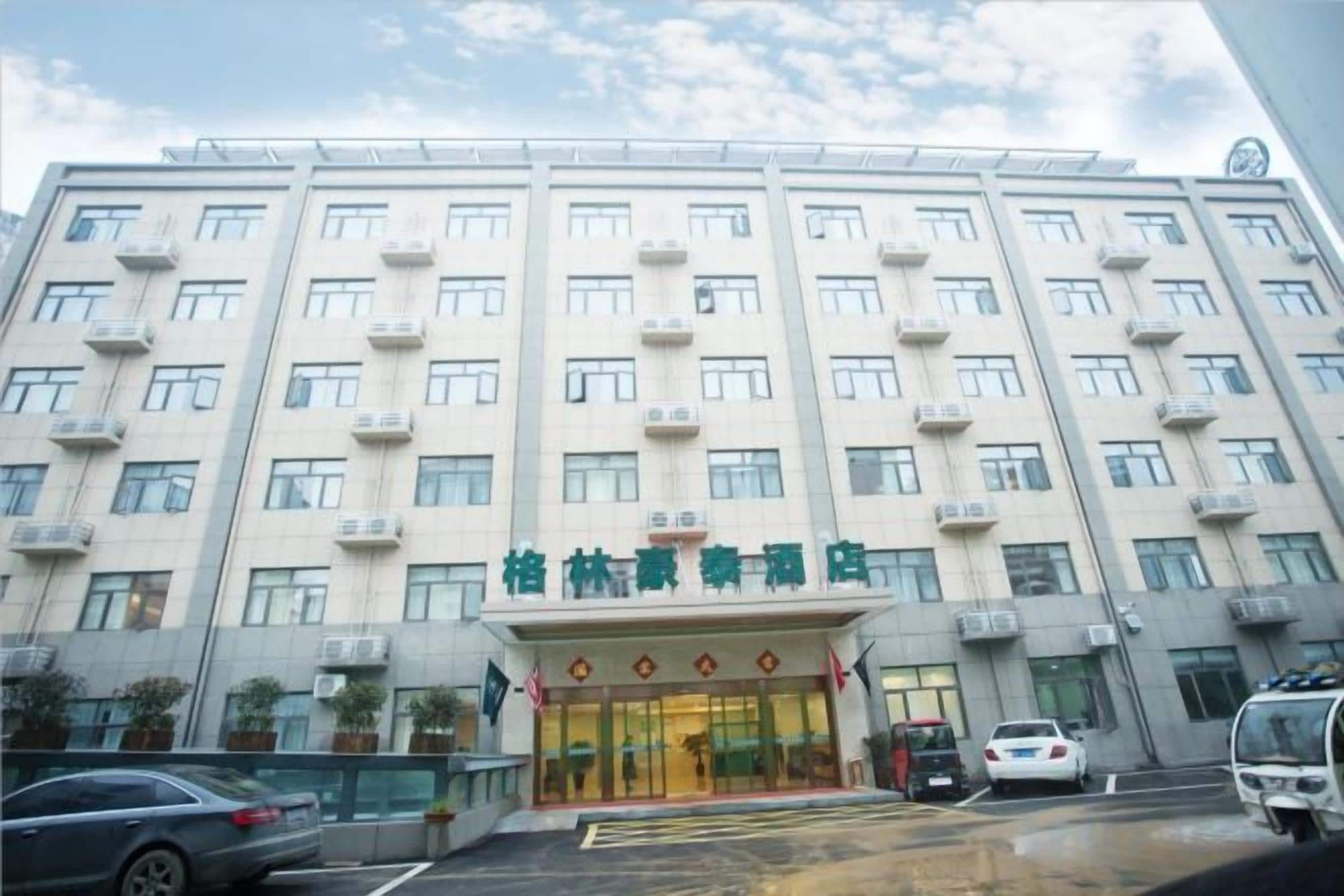 Um hotel com vários andares, entrada central, aparelhos de ar condicionado e estacionamento.