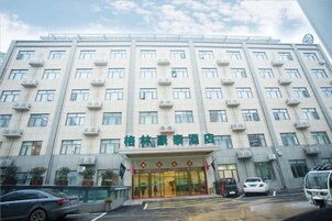 A multi-story hotel with a central entrance, air conditioning units, and a parking area.